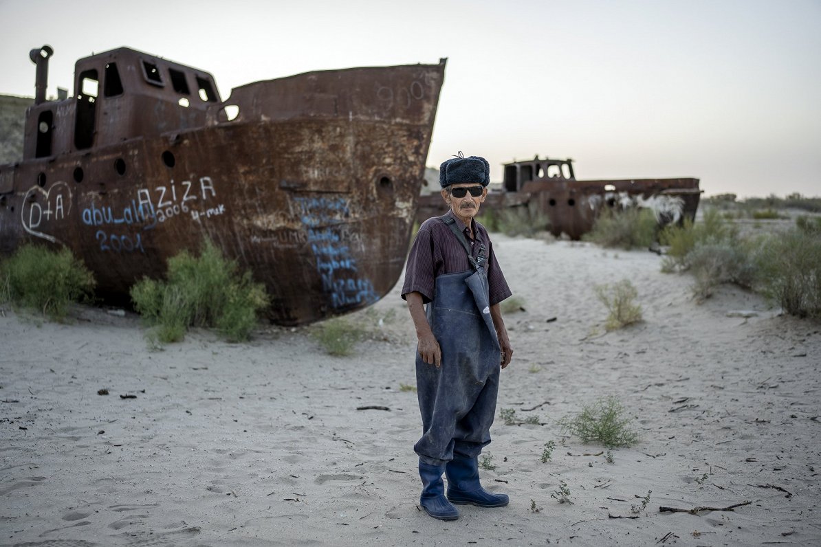 Uzbekistānā bijušais zvejnieks Džovads Hāns pozē pie savas vecās zvejas laivas
