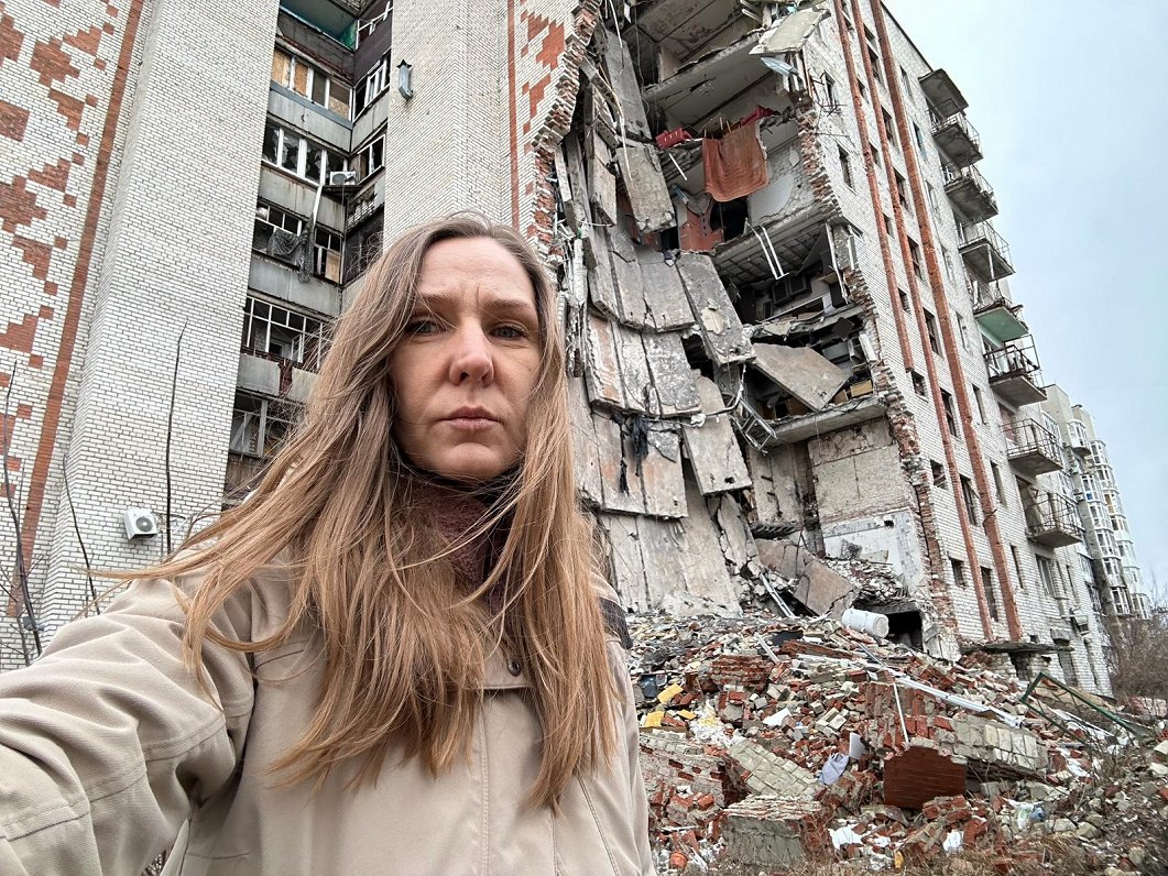 Latvijas Radio korespondente Indra Sprance pie karadarbībā sagrautām ēkām Ukrainas pilsētā Limanā