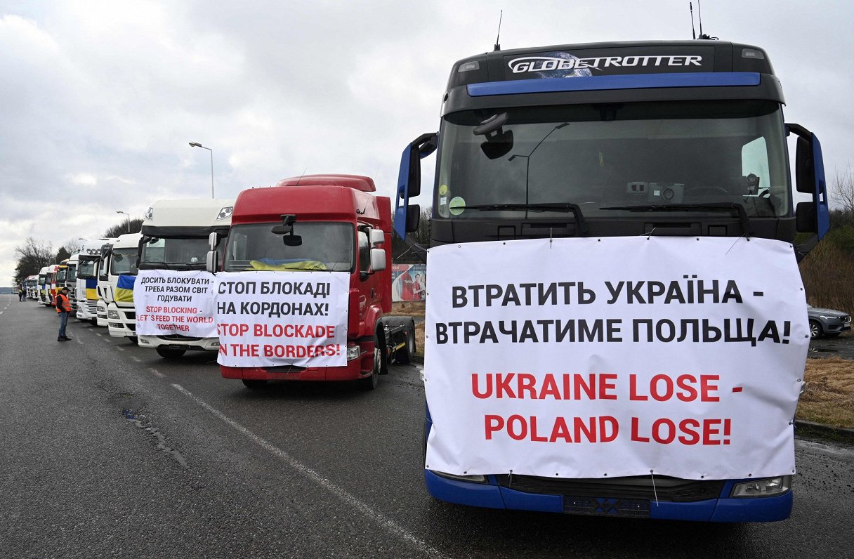 Ukrainas kravu pārvadātāji protestē pret robežas blokādi, ko īsteno Polijas zemnieki. Plakāts vēsta:...