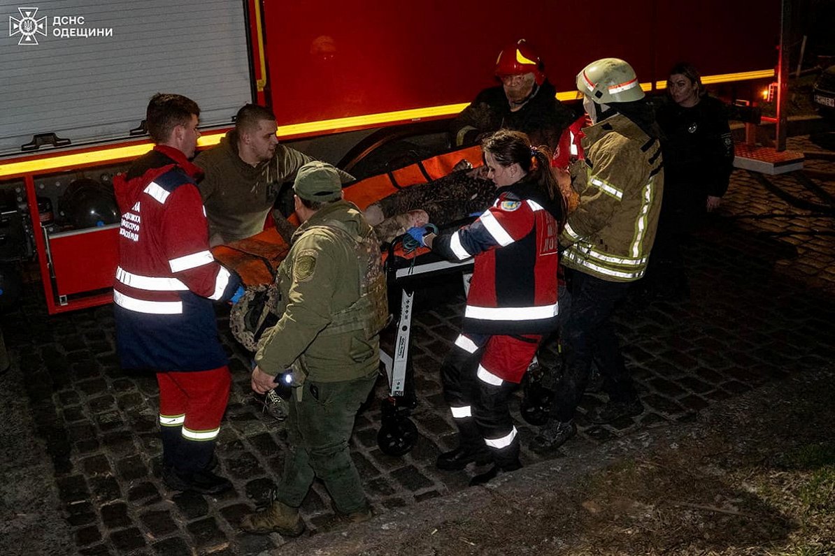 Glābēji palīdz cietušajam pēc dronu uzbrukuma Ukrainas pilsētā Odesā.