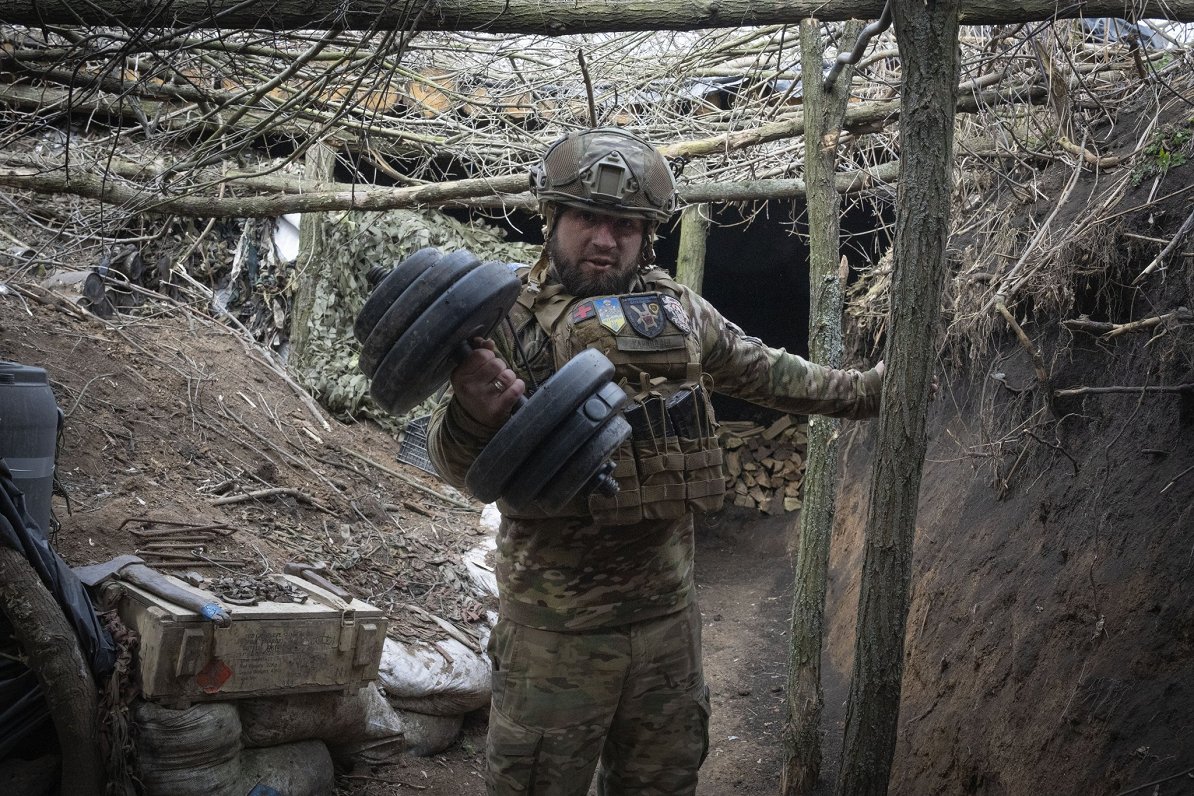 Ukraiņu karavīrs ierakumos netālu no Bahmutas demonstrē savu hanteli