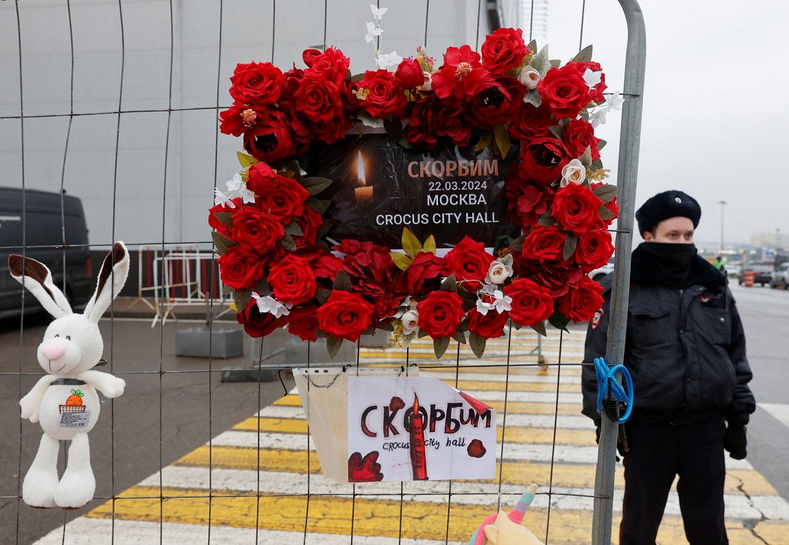 Сотрудник полиции рядом с импровизированным мемориалом у «Крокус Сити Холла» 23 марта 2024 года