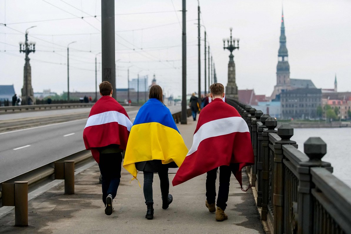Cilvēki ar Latvijas un Ukrainas karogiem Rīgas ielās