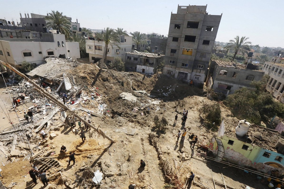Cilvēki pārmeklē Izraēlas gaisa triecienos sagrautu ēku drupas