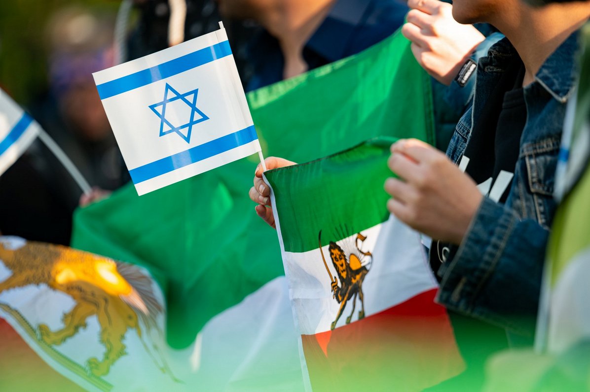 Hamburga: sieviete mītiņā pretī Irānas konsulātam tur Izraēlas un Irānas karogu.