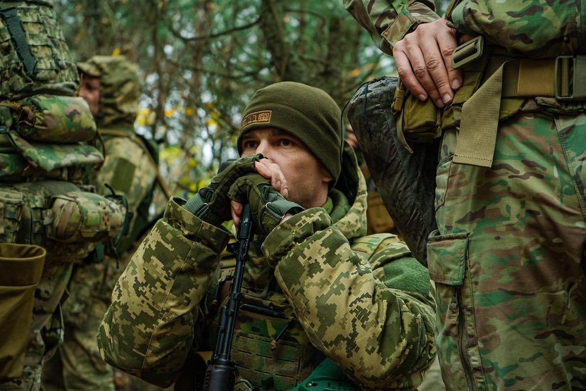 Ukrainas armijas karavīrs vēro mākslinieka uzstāšanos.