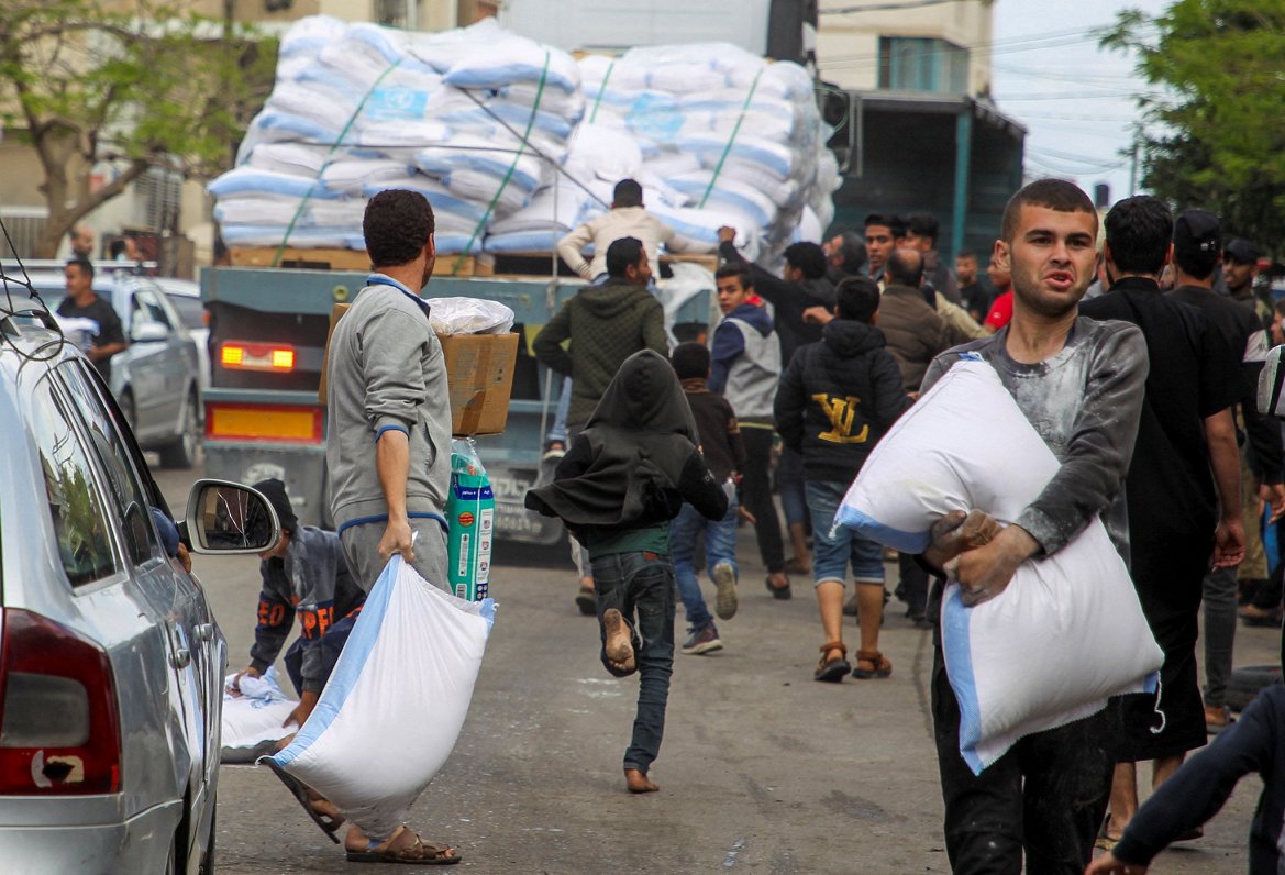 Cilvēki Rafahā tver miltu maisus no kravas auto pēc tam, kad Izraēlas militārpersonas sāka evakuēt p...