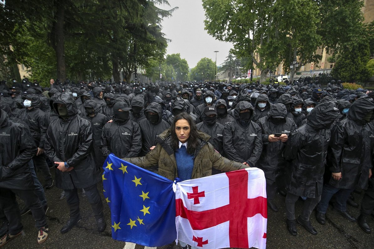 Protestētāja ar Eiropas Savienības un Gruzijas karogiem. Taču protesti neapturēja tā sauktā &quot;ār...