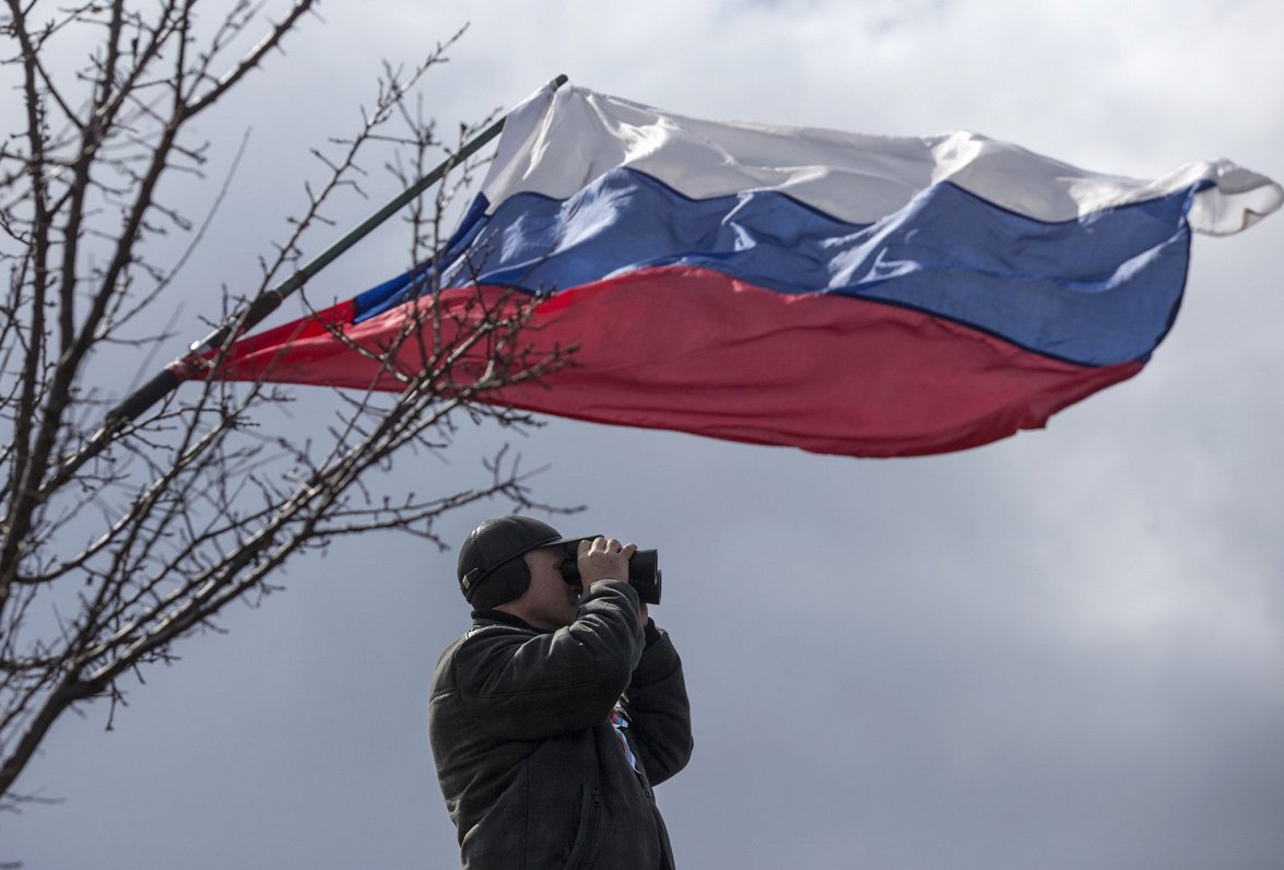 Cilvēks ar binokli zem Krievijas karoga.