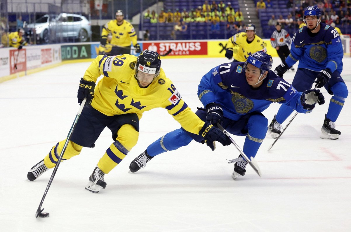 Zviedrijas hokejists Markuss Sorensens (pa kreisi) spēlē pret Kazahstānu
