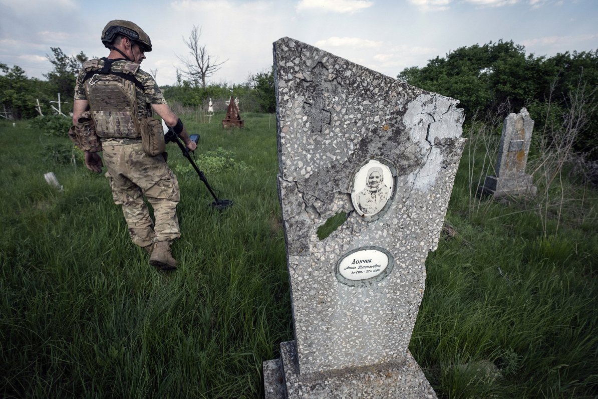 Ukrainas sapieris pārmeklē kapsētas teritoriju, kur risinājušās smagas cīņas