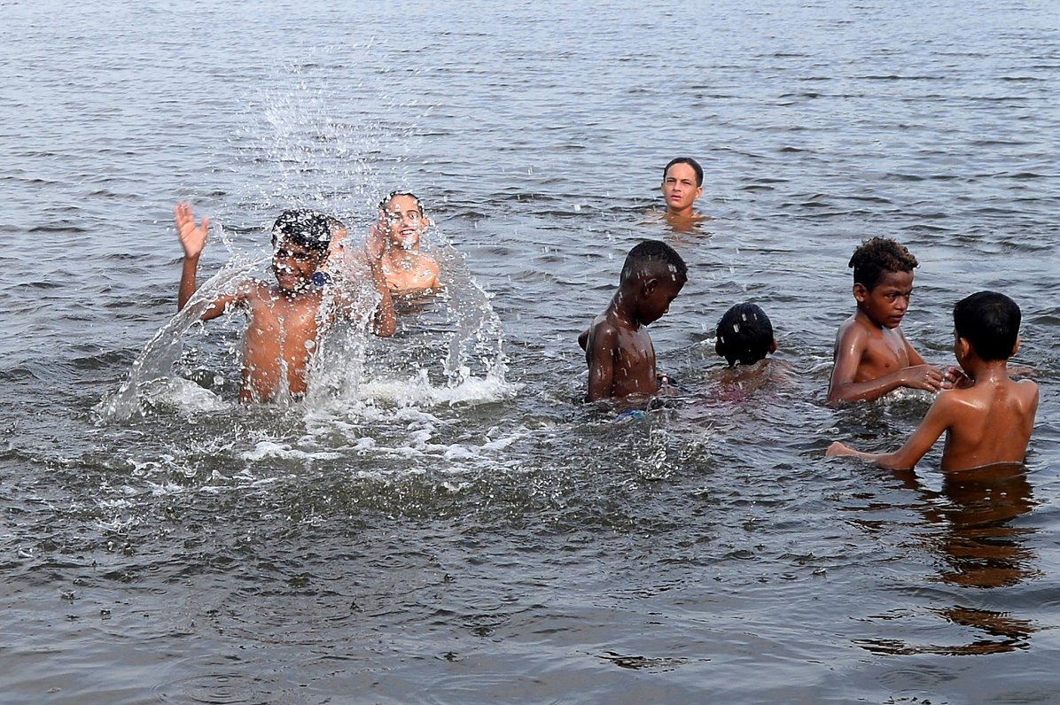 Cilvēki vasaras svelmē Pakistānā veldzējas ūdenstilpē