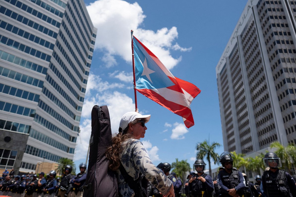 Sieviete ar Puertoriko karogu Sanhuanas pilsētas centrā.