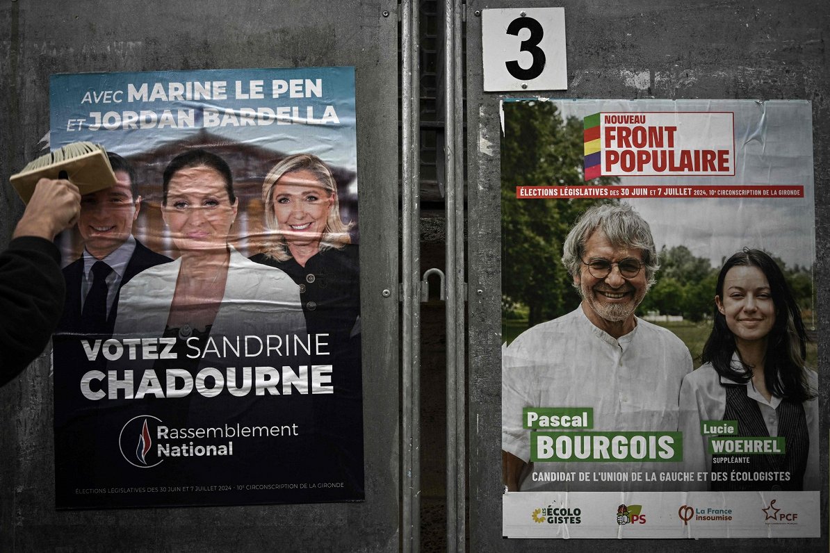 Priekšvēlēšanu kampaņas dalībnieks līmē Francijas labējo populistu Nacionālās apvienības plakātu Lib...