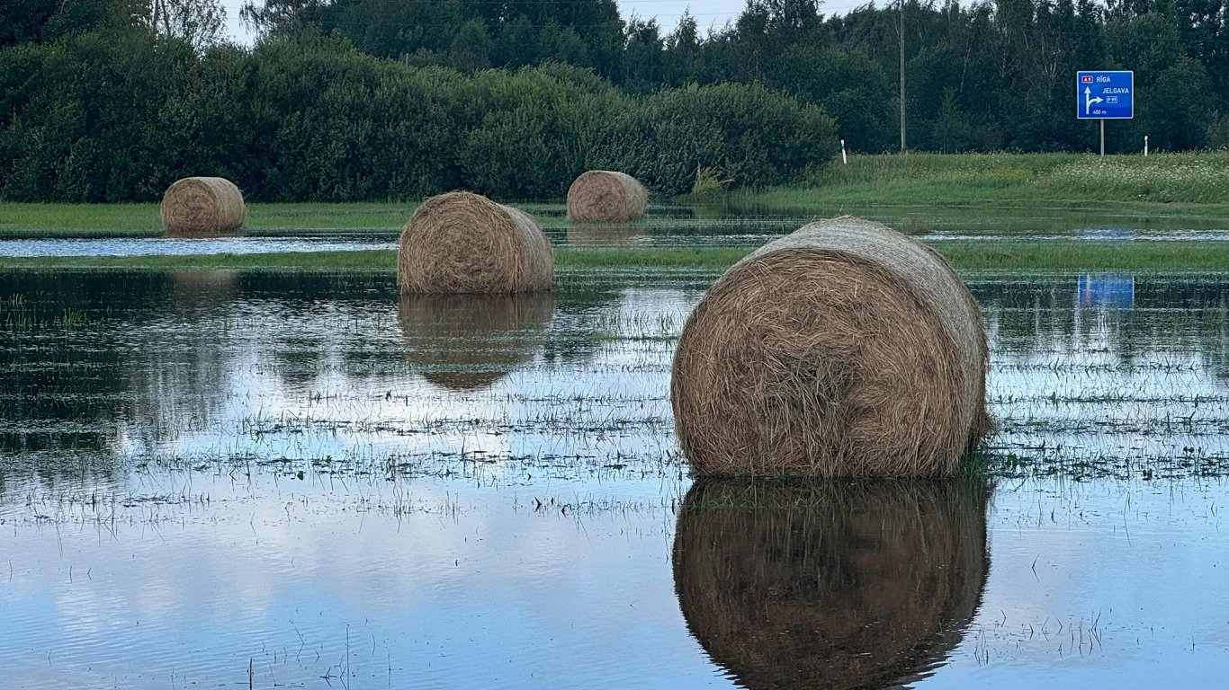 Pēc lietus applūdušā pļavā mirkst siena ruļļi