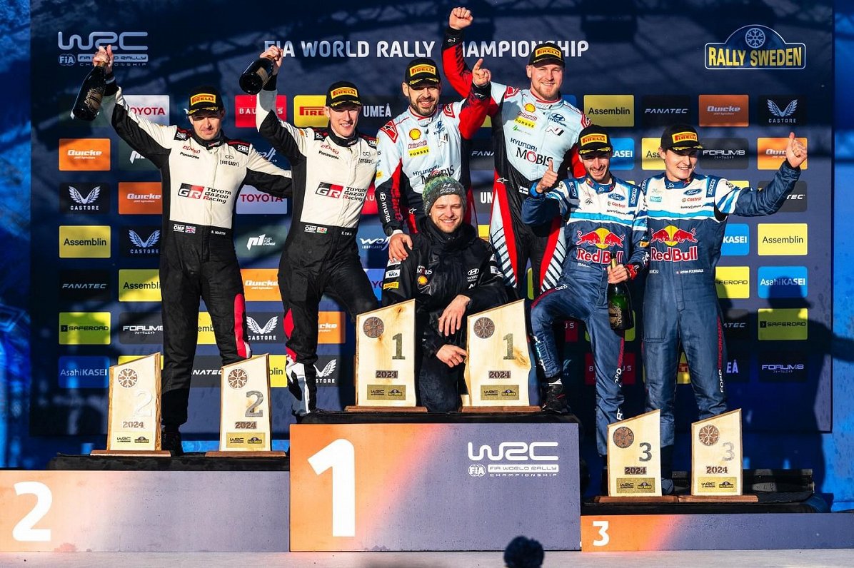 Arturs Ozoliņš uz goda pjedestāla ar Esapeku Lapi pēc viņa triumfa 2024. gada Zviedrijas WRC posmā.