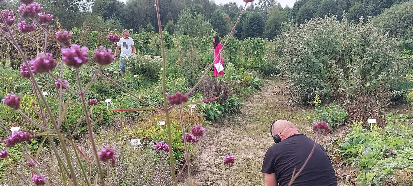 Jānis Ulme iepazīstina Ilzi Ģērmani ar savu dārzu.